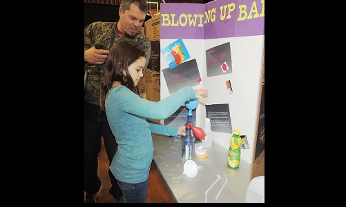 Sage Fiest shows Uncle Jereme her science project-Mar 30 issue Image
